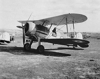 Single-engined military biplane parked on airfield