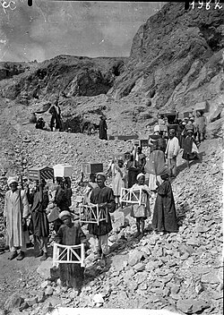 Workers carrying burial goods away from the tomb