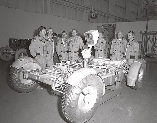 (From left to right) Astronauts John Young, Eugene Cernan, Fred Haise, Charles Duke, Anthony England, Charles Fullerton, and Donald Peterson await deployment tests of the Lunar Roving Vehicle (LRV) qualification test unit in building 4649 at the Marshall Space Flight Center (MSFC). November 1971.