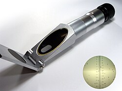 A small cylindrical refractometer with a surface for the sample at one end and an eye piece to look into at the other end
