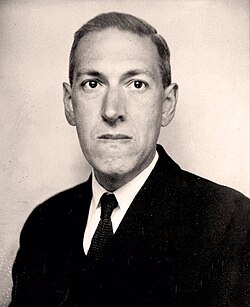Black and white photo of the head and shoulders of a man wearing glasses