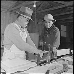 Photo of two incarcerated Japanese Americans using an adjustable mitre box.