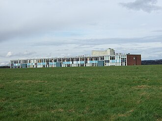 A photo of a long building taken from a field nearby