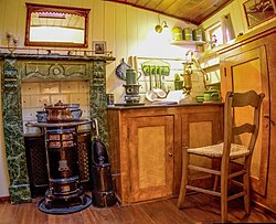 A green marble faux fireplace with a wooden chair and cabinet.
