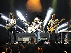Four men perform music in front of an audience.