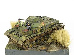 A diorama of a Kugelblitz Self-Propelled Anti Aircraft Gun sitting in a field with dried grass on its sides