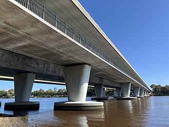 A long concrete bridge crossing a river viewed from below