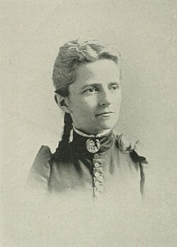 19th-century B&W portrait photo of a woman with her hair in an up-do, wearing a dark, fitted blouse.