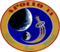 The circular patch depicts the Earth and the Moon. An astronaut lapel pin leaves a comet trail from the liftoff point on Earth. Around it is the logo "Apollo 14 – Shepard Roosa Mitchell"