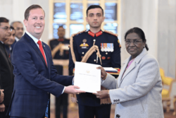 Photograph of Sergio Gord handing a document to Droupadi Murmu