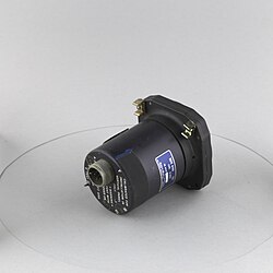 A small black cylindrical part with a square indicator face