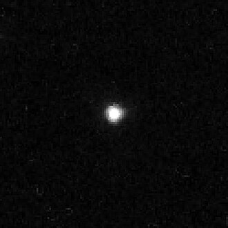 A black-and-white photograph of 2002 XV93 taken by the Hubble Space Telescope on 3 August 2005. In the black backdrop of space, 2002 XV93 appears a lone white dot at the center.