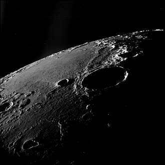 Oblique view facing southeast, from Apollo 11. The large crater right of center is Theophilus, and Mädler is to its left. Fracastorius is near the central horizon, and the white mountain on the horizon at right is part of the Rupes Altai. The teardrop-shaped crater in the lower left is Torricelli.