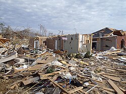 EF3 damage example--A few parts of affected buildings are left standing. Well-built structures lose all outer and some inner walls. Unanchored homes are swept away, and homes with poor anchoring may collapse entirely. Trains and train cars are all overturned. Small vehicles and similarly sized objects are lifted off the ground and tossed as projectiles. Wooded areas suffer an almost total loss of vegetation and some tree debarking may occur.