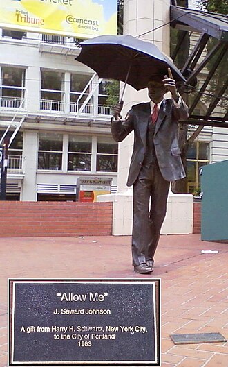 A bronze statue of a man in a business suit; in one hand he is holding an umbrella, while his other arm is extended.