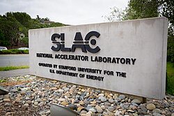 A concrete monument sign reads "SLAC National Accelerator Laboratory: Operated by Stanford University for the U.S. Department of Energy".