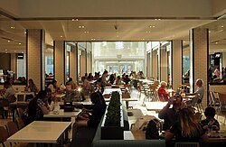 People sitting at tables in the food court of a shopping mall