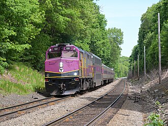 A passenger train pulling on a double track line with trees on both sides