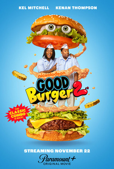 A giant-sized buger, with two fast food workers standing in the middle.