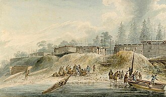 A forested coastline with several buildings, and two boats pulled up on the beach