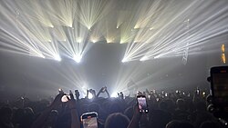 Intense lighting effects during a performance by rapper OsamaSon in 2025. The image displays bright lights that add a silhouette effect to the performing artist.