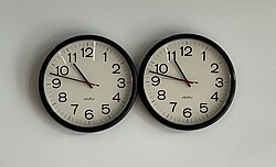Two clocks on a white wall