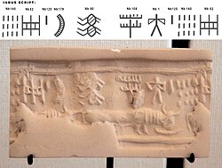 Impression of an Indus cylinder seal discovered in Susa, in strata dated to 2400–2100 BC. Elongated buffalo with line of standard Indus script signs. Tell of the Susa acropolis. Louvre Museum, reference Sb 2425.[58][59] Indus script numbering convention per Asko Parpola.[60][61]