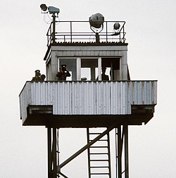 A metal observation tower manned by three GDR guards.
