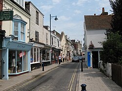 A narrow paved road, lined with shops