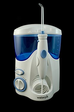 A countertop oral irrigator with a water reservoir and a handle with a nozzle.
