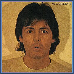 A yellow-tinted photograph of Paul McCartney at shoulder-length giving a confused or ambivalent expression.