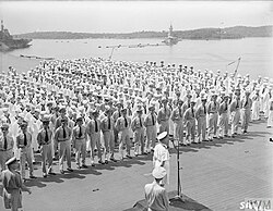 Black and white photo of men in military uniforms on the deck of an aircraft carrier